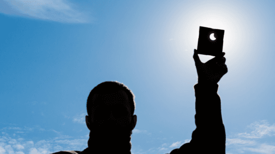 Man holding up a piece of paper to the sun